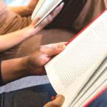 Two high school students reading books to prepare for a college entrance exam.