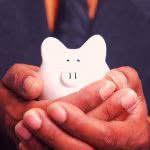 Parent holding a small piggy bank in his hands.