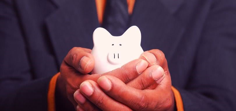 Parent holding a small piggy bank in his hands.