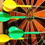 Yellow and green darts on a target board.
