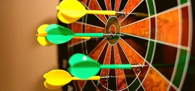 Yellow and green darts on a target board.