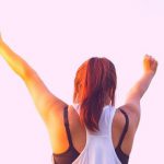 A high school student with her arms in the air doing a victory pose.