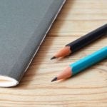 Two pencils on a desk next to a gray boolet.