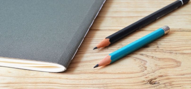Two pencils on a desk next to a gray boolet.