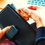 A person holding a wallet and pulling out a credit card.