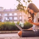 College student researching financial aid on her laptop at campus.