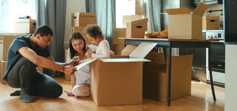 Parents playing in moving boxes with their daughter. They're thinking about 529 savings plans for her future education.