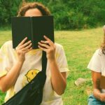 Two high school seniors reading outside during summer to prep for college.