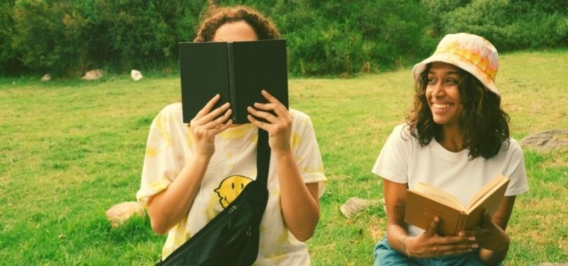 Two high school seniors reading outside during summer to prep for college.