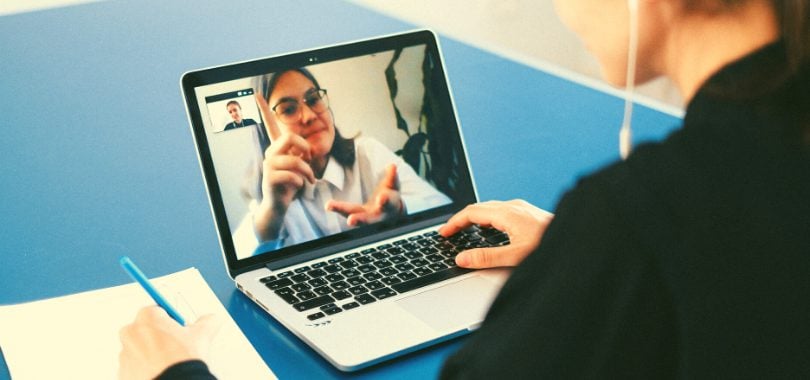 A student watches a professor on her laptop during an online class in her hybrid program.