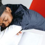 A student is asleep at his desk with books while studying for the ACT