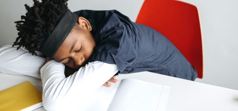 A student is asleep at his desk with books while studying for the ACT